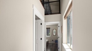 Un couloir étroit avec un escalier menant à l’étage supérieur.