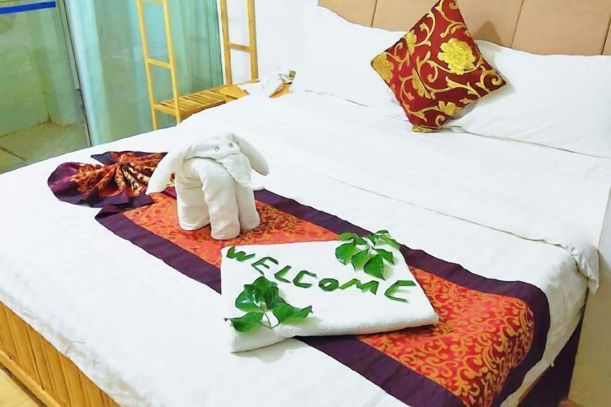 A bed with a welcome mat, a plush toy, and a decorative pillow.