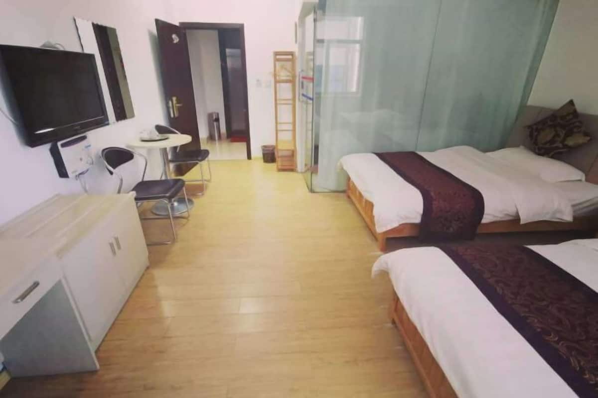 A hotel room with two beds, a TV, a desk, and a wardrobe.