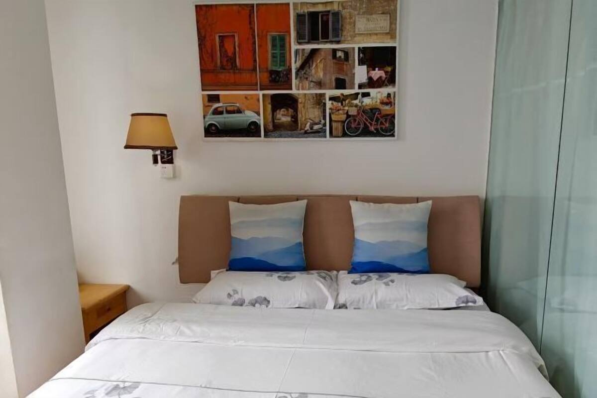 A bed with a headboard, a nightstand, a wall-mounted lamp, and a collage of images above the bed.