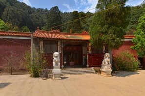 A traditional building with a red roof and a statue in front.