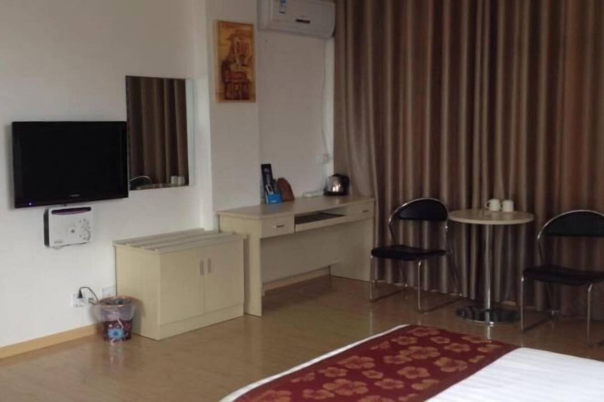 Relax in a cozy space with a comfortable bed, desk, and TV, plus a window with curtains and air conditioning for a comfortable stay.