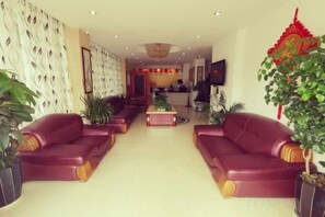 A hotel lobby with leather sofas, a reception desk, and potted plants. - Fuxian Lake Coastline Express Hotel (Luchong Scenic Area) (Chengjiang)
