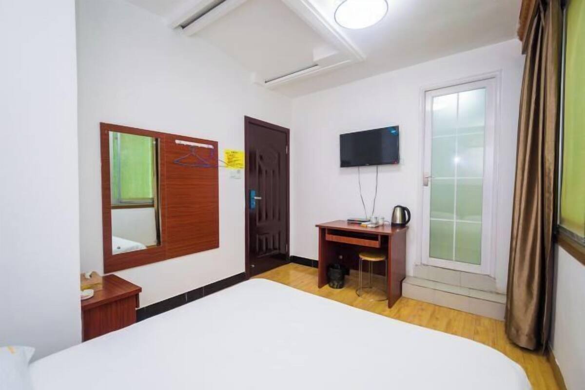 A hotel room with a bed, a desk, a television, and a window with curtains.