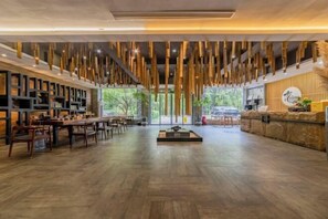 Un vestíbulo amplio con suelo de madera, una recepción y un área de descanso.