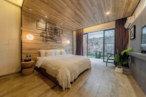Une chambre moderne avec un plafond en bois, un grand lit, une table de chevet, une télévision et une vue sur l’extérieur.