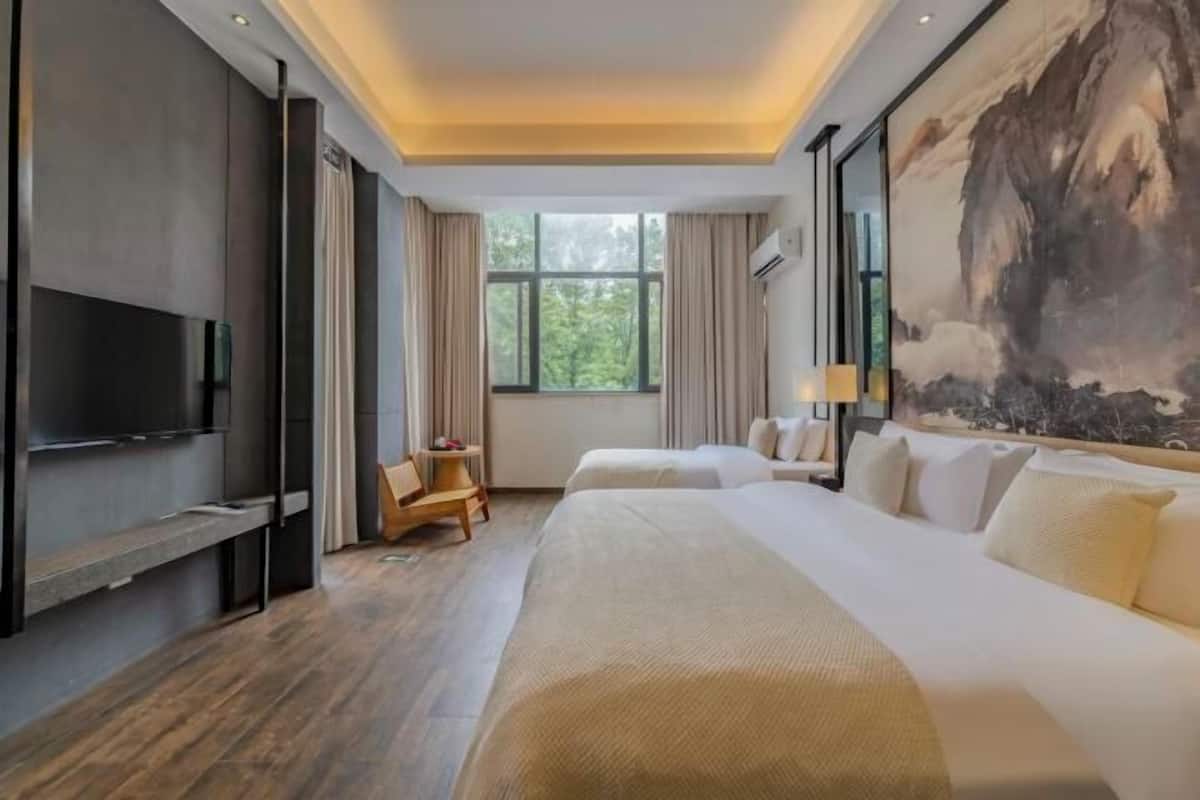 Une chambre d’hôtel avec un grand lit, une télévision, un bureau et un tableau au mur.