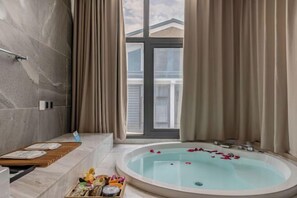 Une salle de bain moderne avec une baignoire, un espace douche et une fenêtre avec des rideaux.