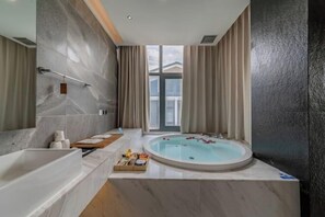 Une salle de bain moderne avec une baignoire, une grande fenêtre et un jacuzzi.