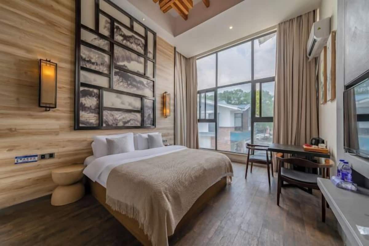 Une chambre d’hôtel avec un grand lit, un bureau et une vue sur l’extérieur.