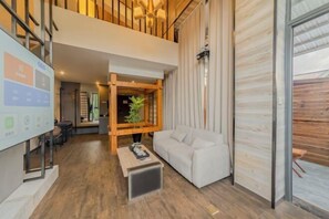 A modern interior with a sofa, coffee table, wooden structure, and a plant.