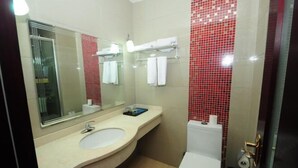 Un baño con lavabo, espejo, inodoro y paredes con azulejos rojos.