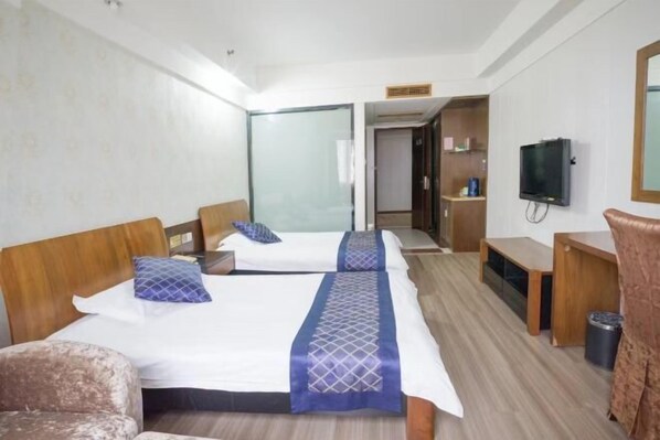 A hotel room with two beds, a TV, a desk, and a trash can.