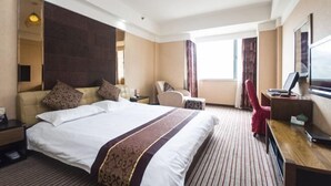 Una habitación de hotel con una cama grande, un escritorio, una silla, un televisor y una ventana.