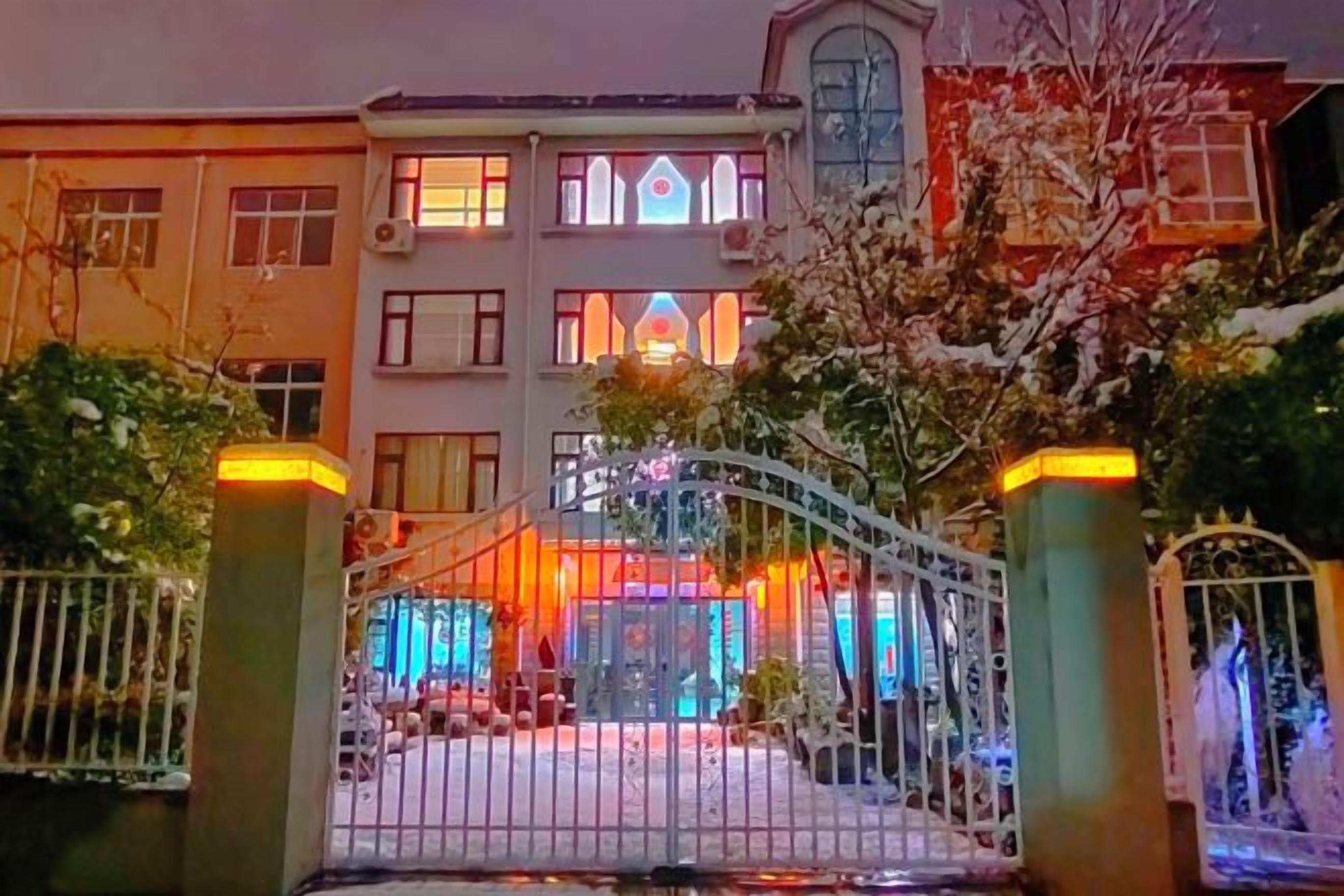 Un hôtel doté d’une entrée sécurisée par un portail, de nombreuses fenêtres et d’une façade bien éclairée.