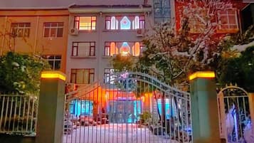 A hotel with a gated entrance, multiple windows, and a well-lit facade.
