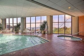 An indoor swimming pool with clear views of the surrounding landscape through large windows.