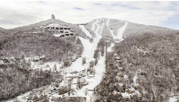 A snow-covered mountain with a ski lift, cabins, and a lodge.