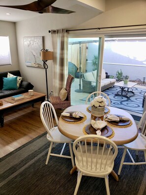 Un salon comprenant un canapé, une table à manger avec des chaises, un lampadaire et une vue sur l’extérieur.