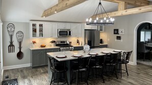 Una cocina moderna con armarios blancos, una isla central con taburetes de bar y un techo de madera.