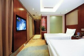 A hotel room with two beds, a television mounted on the wall, a plant, and a small table with a lamp. - Kunming Shuitian Hot Spring Hotel (Kunming)