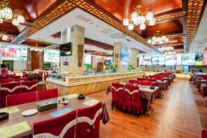 A restaurant with multiple dining tables and chairs, a counter with a menu, and a bar area. - Kunming Shuitian Hot Spring Hotel (Kunming)