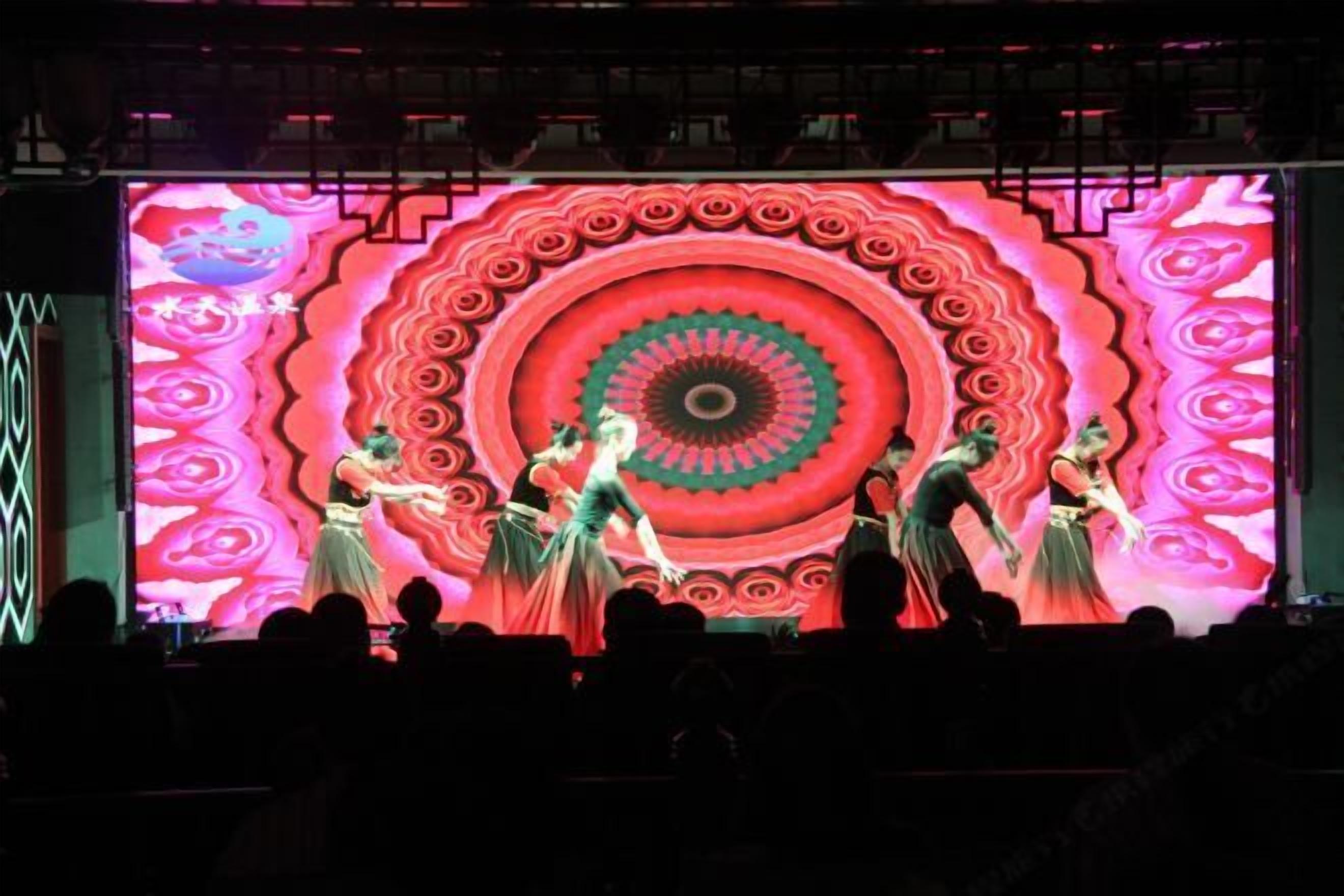 A stage with dancers performing in front of a large, colorful backdrop.