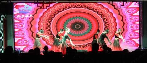 A stage with dancers performing in front of a large, colorful backdrop.