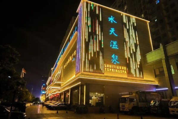 A hotel with illuminated vertical lines and signage in a foreign language, indicating a permanent feature. - Kunming Shuitian Hot Spring Hotel (Kunming)