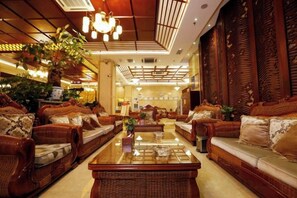 A spacious lobby with wicker furniture, a central coffee table, and a large plant. - Kunming Shuitian Hot Spring Hotel (Kunming)