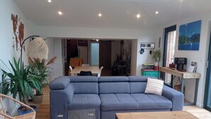Ein modernes Wohnzimmer mit einer Eckcouch, einem Holztisch und einem Essbereich im Hintergrund.