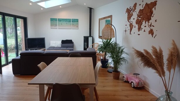 Ein modernes Wohnzimmer mit einem Holzesstisch, einer Couch, einem Fernseher und einer Weltkarte an der Wand.