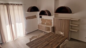 A dining area with a wooden table and white chairs, a stone wall, and built-in shelves with arched openings.