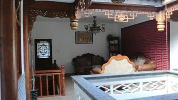Una habitación tradicional con techo de madera, cama con cabecera blanca, separador rojo y candelabro.