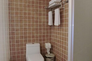 A bathroom with a toilet, a paper towel dispenser, and a towel rack with towels. - Dongshan Courtyard Inn (Chengdu)