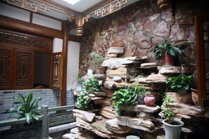 Un interior tradicional con pared de piedra, puerta de madera y plantas en macetas.