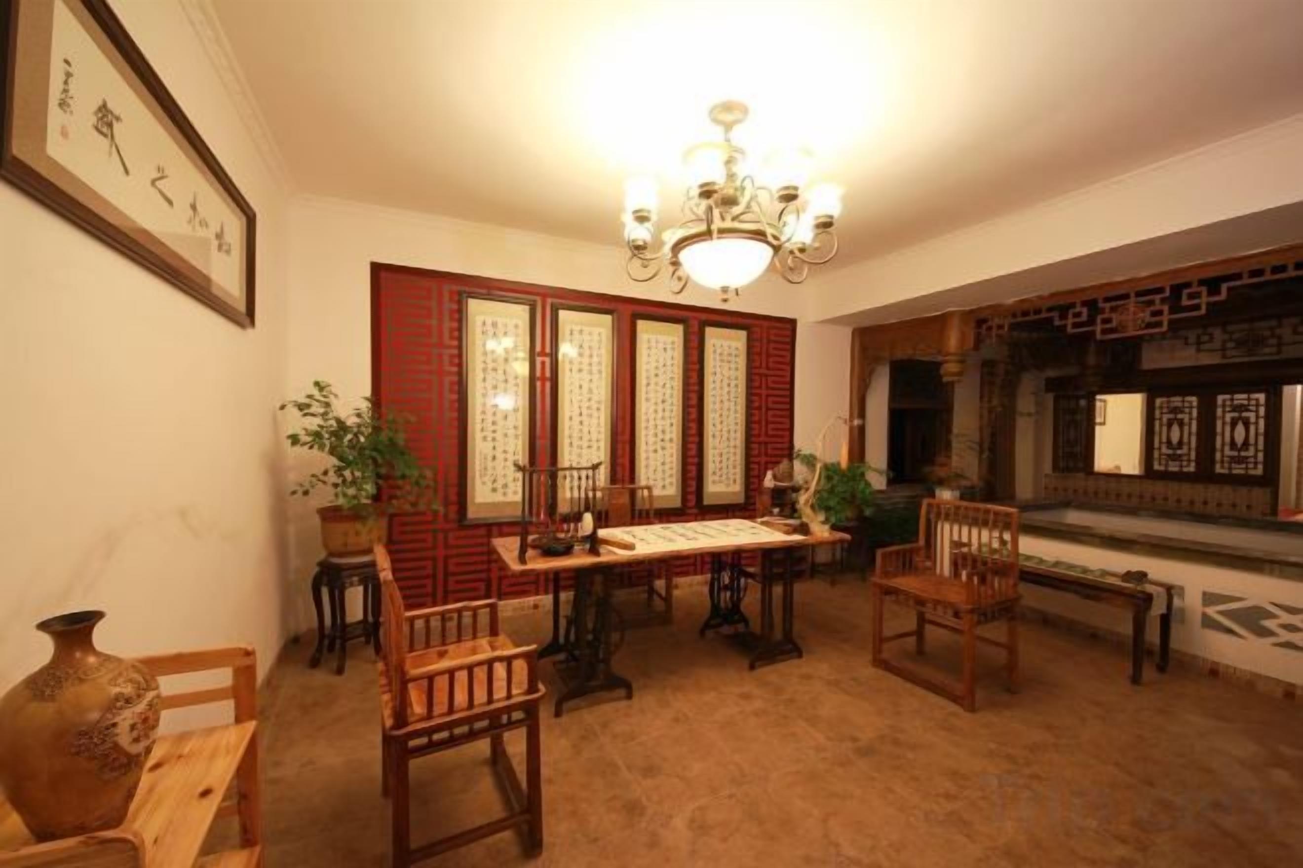 Una habitación tradicional con una mesa de madera, sillas, una lámpara de araña y un biombo decorativo.