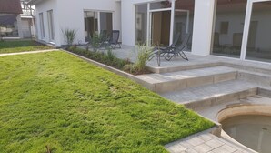 A modern house with a well-maintained lawn, a small garden area with plants, and a pool.