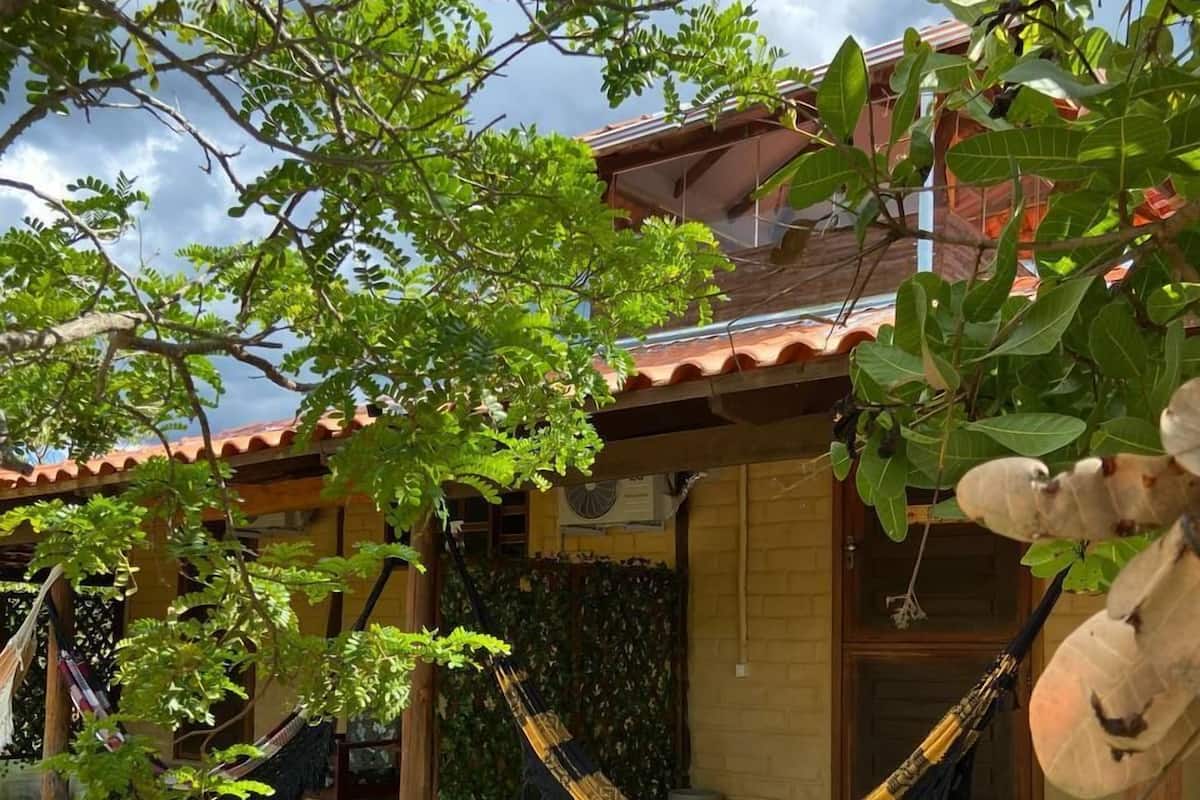 Una casa tradicional con techo de tejas, una hamaca y un pequeño jardín.