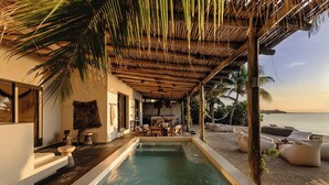 A poolside area with a wooden pergola, outdoor seating, and a view of the ocean. - Villa Blanca, Tulum – Beachfront • Chef Included (Tulum)