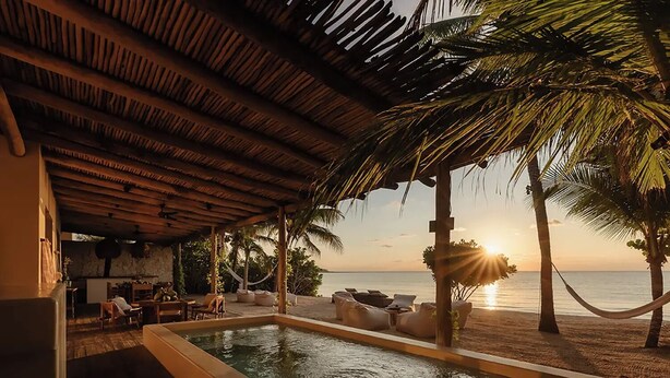 A pool area with lounge chairs and a view of the sunset over the ocean. - Villa Blanca, Tulum – Beachfront • Chef Included (Tulum)