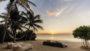 A beach with a hammock, a lounge chair, and a small table. - Villa Blanca, Tulum – Beachfront • Chef Included (Tulum)