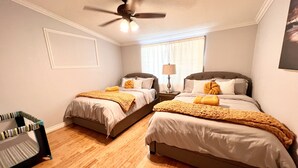 A bedroom with two beds, a ceiling fan, a window with blinds, and a nightstand with a lamp. - 🏡 Joyful Vacation Home 🏡  (Anaheim)