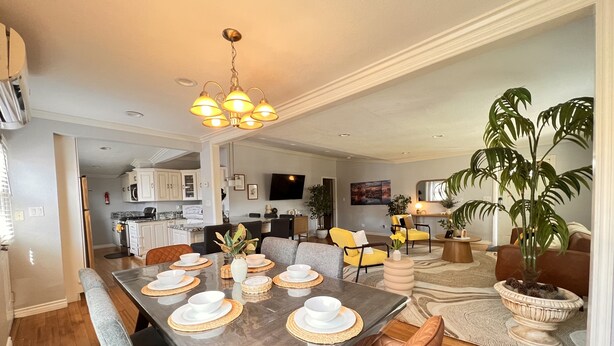 A dining area with a long table set for four, surrounded by chairs, and a kitchen in the background. - 🏡 Joyful Vacation Home 🏡  (Anaheim)