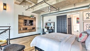 Un dormitorio moderno con una cama grande, una pared de acento de madera, un tocador con espejo y un ventilador de techo.