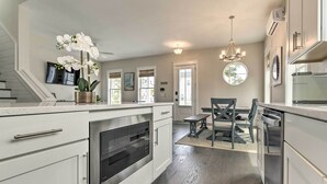 A modern kitchen with white cabinetry, a built-in oven, and a dining area with a bench and table. - Inlet Beach Cottage: Close to Beach Access! (Inlet Beach)