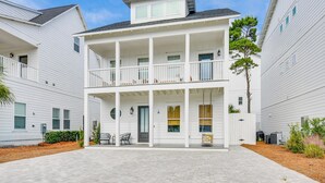 A two-story building with a covered front porch and a small outdoor seating area. - Inlet Beach Cottage: Close to Beach Access! (Inlet Beach)