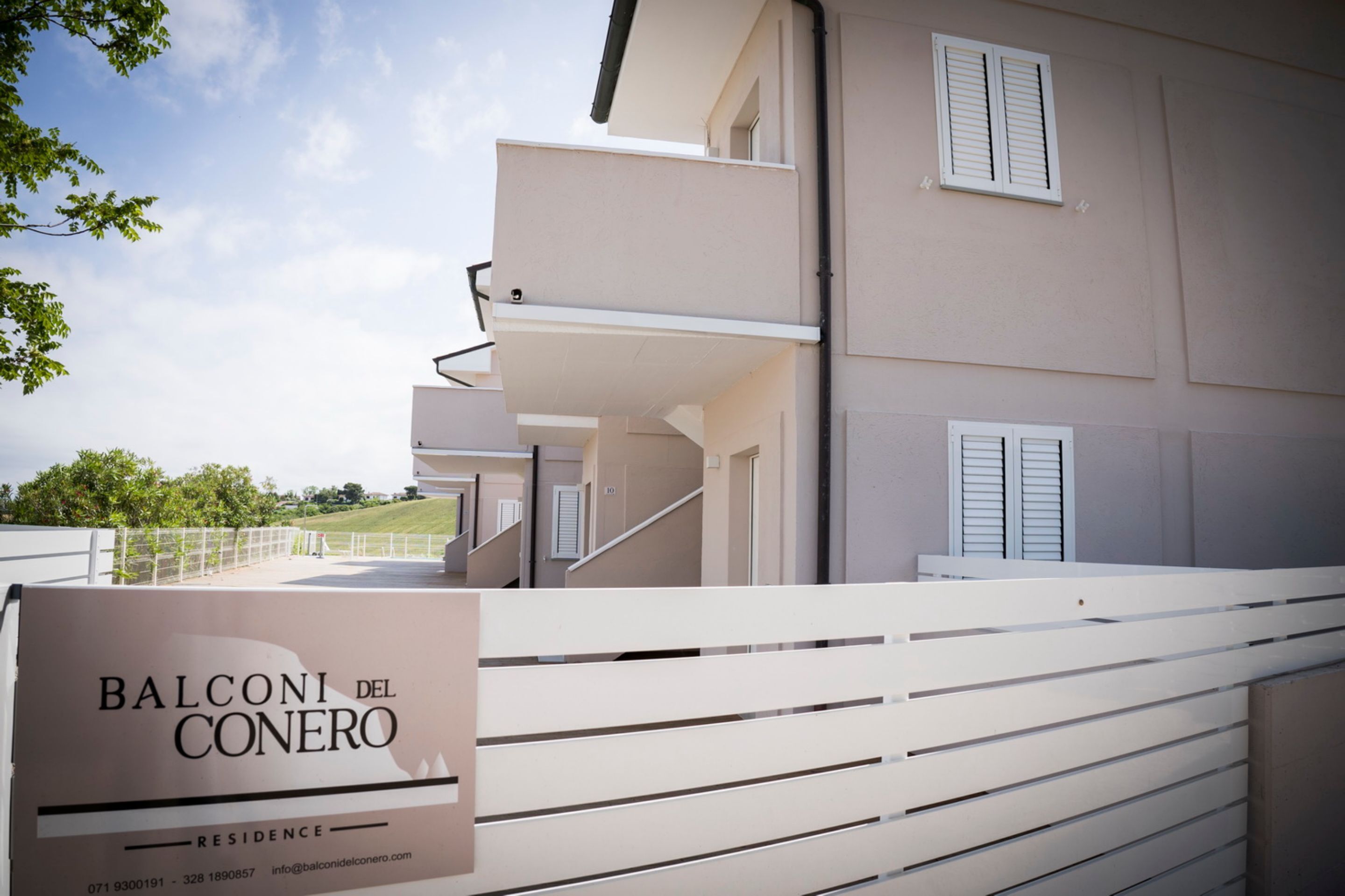 Ein Wohngebäude mit Balkon, Treppe und einem Schild mit der Aufschrift 'BALCONI DEL CONERO'.