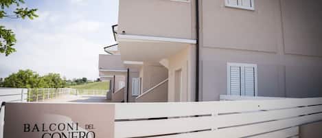 A residential building with a balcony, a staircase, and a sign indicating 'BALCONI DEL CONERO'.