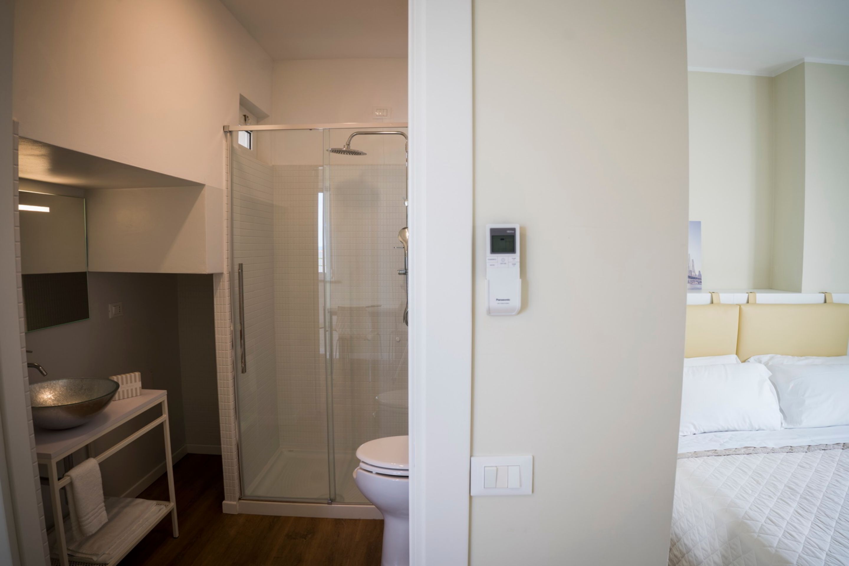 Uma casa de banho moderna com chuveiro em cabine de vidro, uma pia branca e uma sanita.